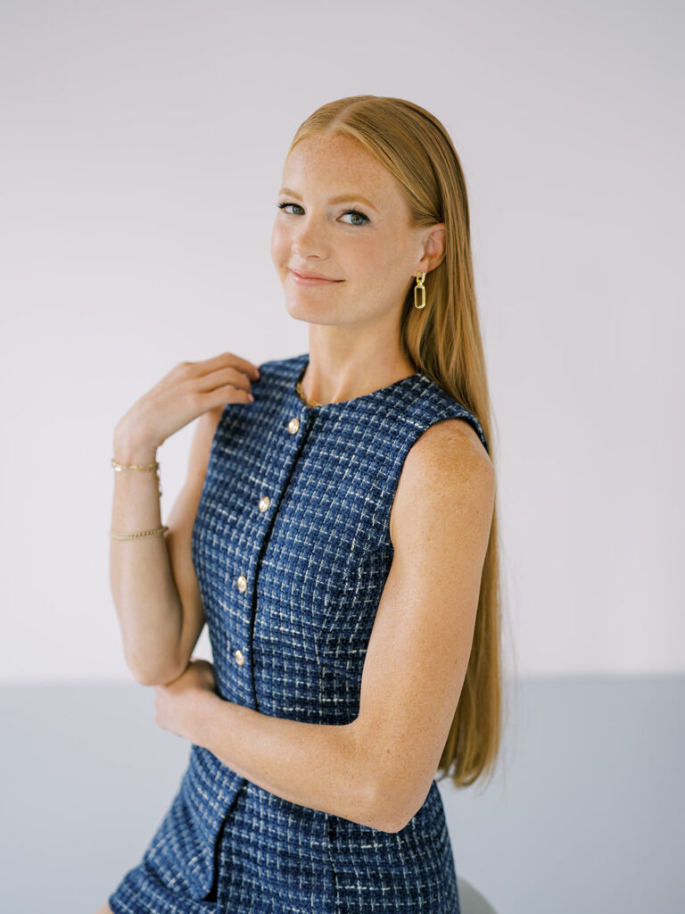 Sophisticated portrait of Autumn, redhead associate photographer with Lauren Bliss Photography, wearing a navy blue tweed set in NYC studio