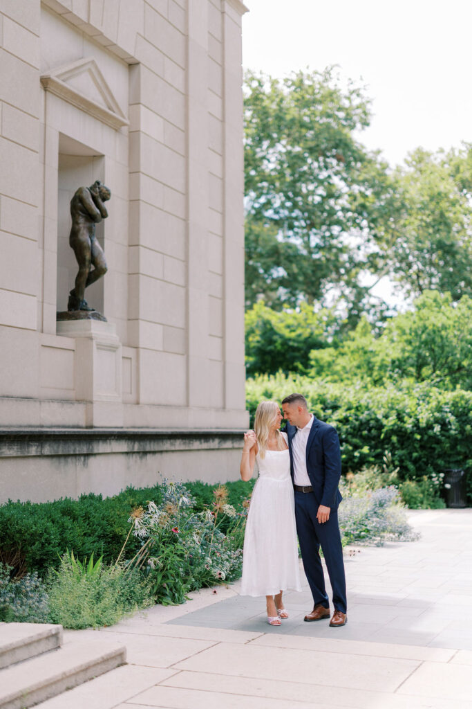 A tender moment between Kelsey and Lee as they lean in close beside one of the Rodin Museum’s iconic sculptures, framed by soft greenery.
