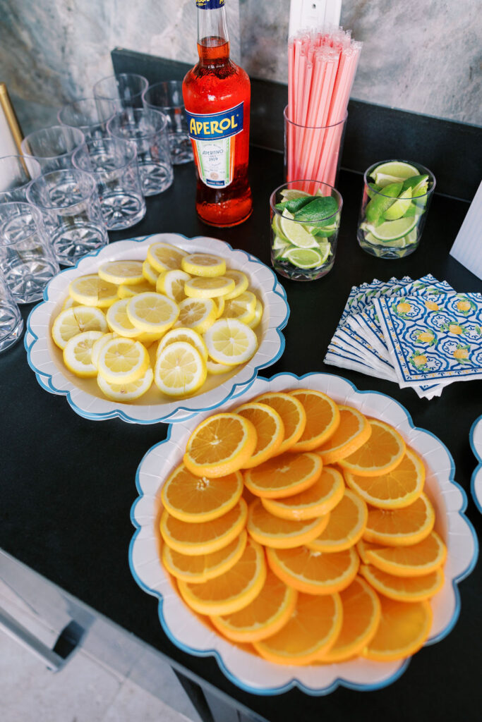 Citrus slices, glassware, and Aperol arranged for a coastal event bar setup during a 30A retreat weekend.