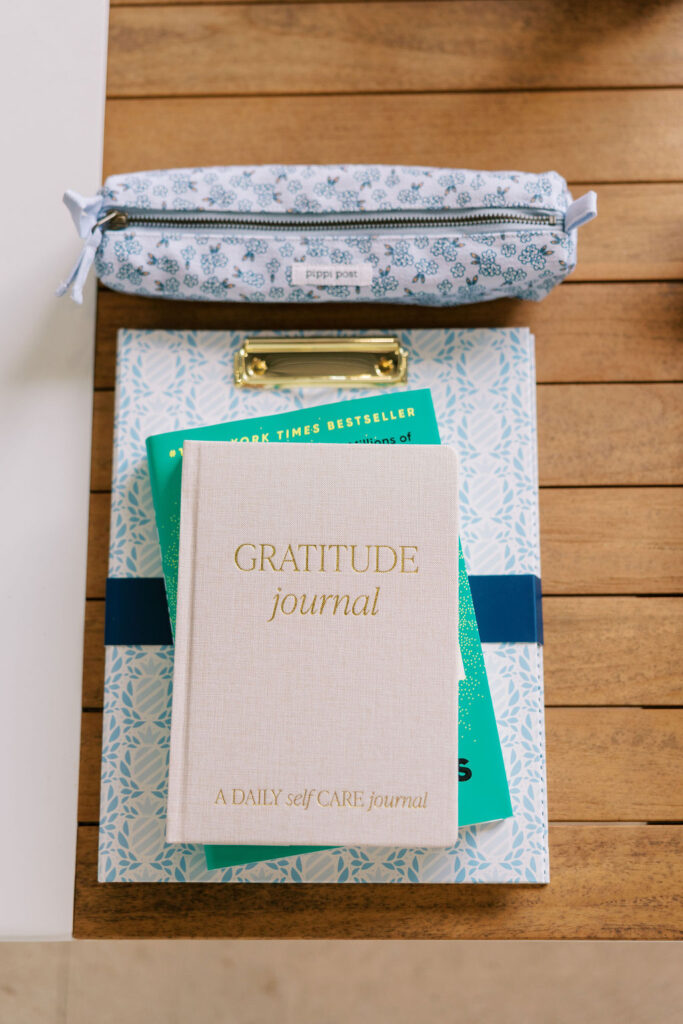 Flatlay of gratitude journal, books, and stationery styled as guest materials for a coastal 30A retreat.