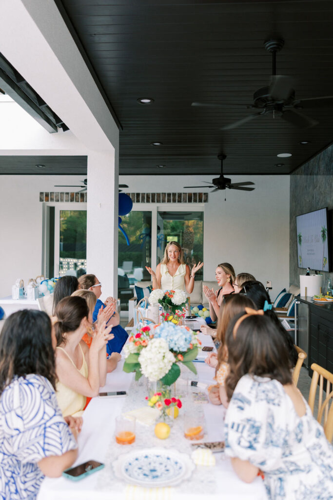 Retreat leader teaching at a long tablescape surrounded by florals, guests, and coastal event decor during a 30A retreat workshop.