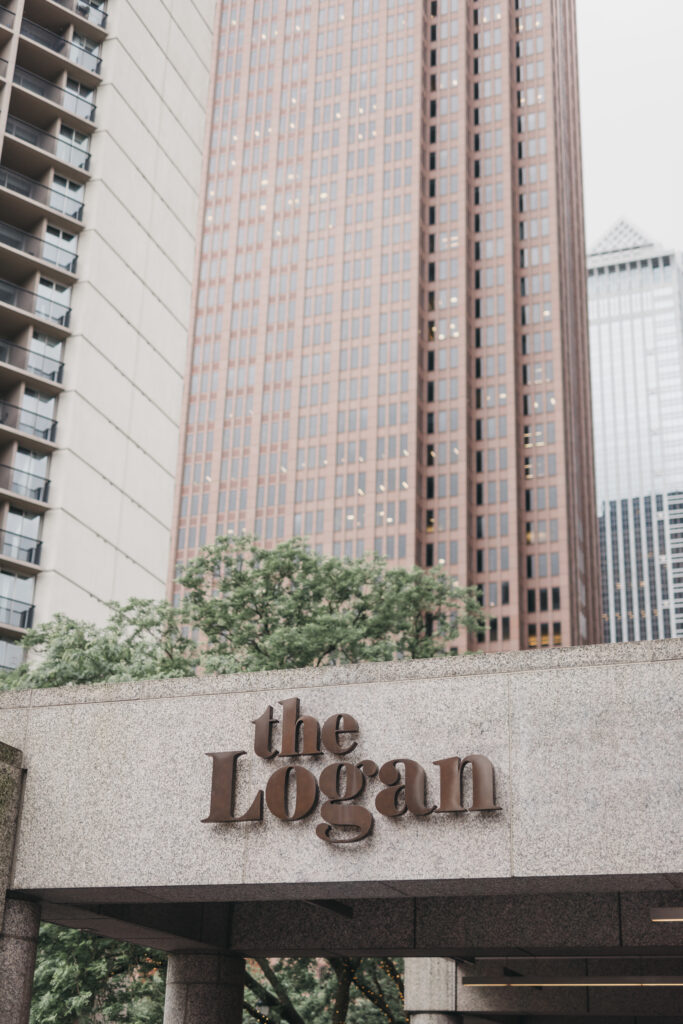 Exterior sign of The Logan Hotel in Philadelphia with surrounding skyscrapers, photographed for a Pennsylvania wedding venue guide by Lauren Bliss Photography.