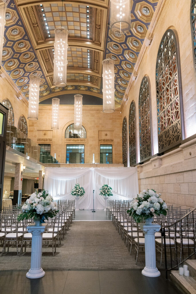 Grand ceremony setup inside Union Trust with tall floral arrangements, draped backdrop, and ornate vaulted ceiling, captured by Lauren Bliss Photography for a Philadelphia Area Venue Guide