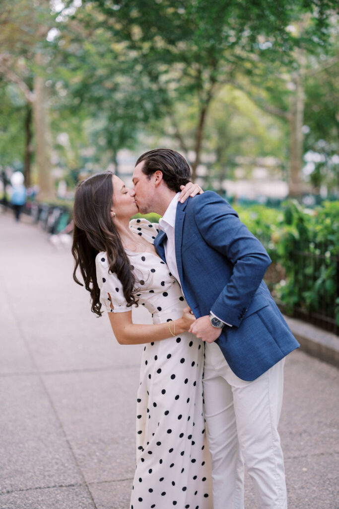 Couple kisses on the sidewalk next to Rittenhouse Square park in Philadelphia
