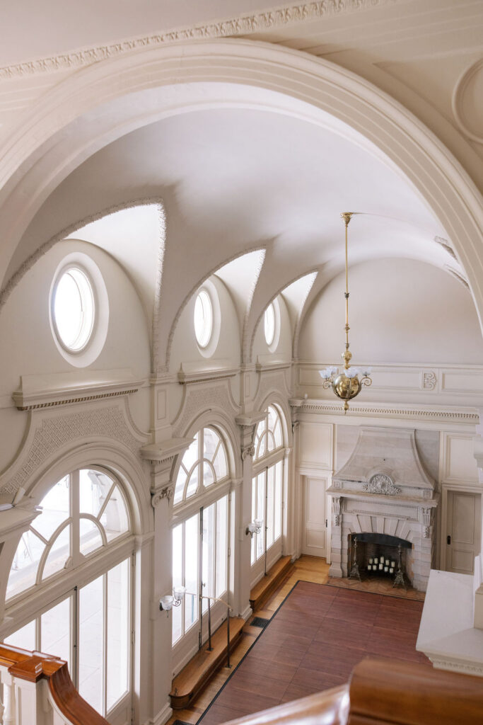 Vaulted hall with arched windows, round oculus windows, and marble fireplace at Cairnwood Estate wedding venue