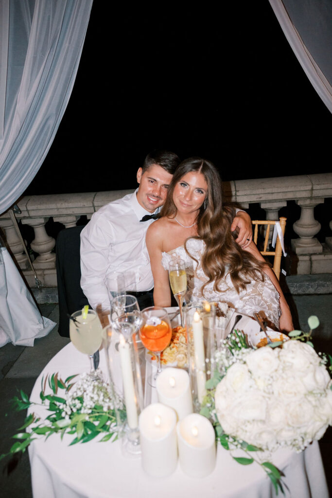 Bride and groom at their candlelit sweetheart table on the terrace at night