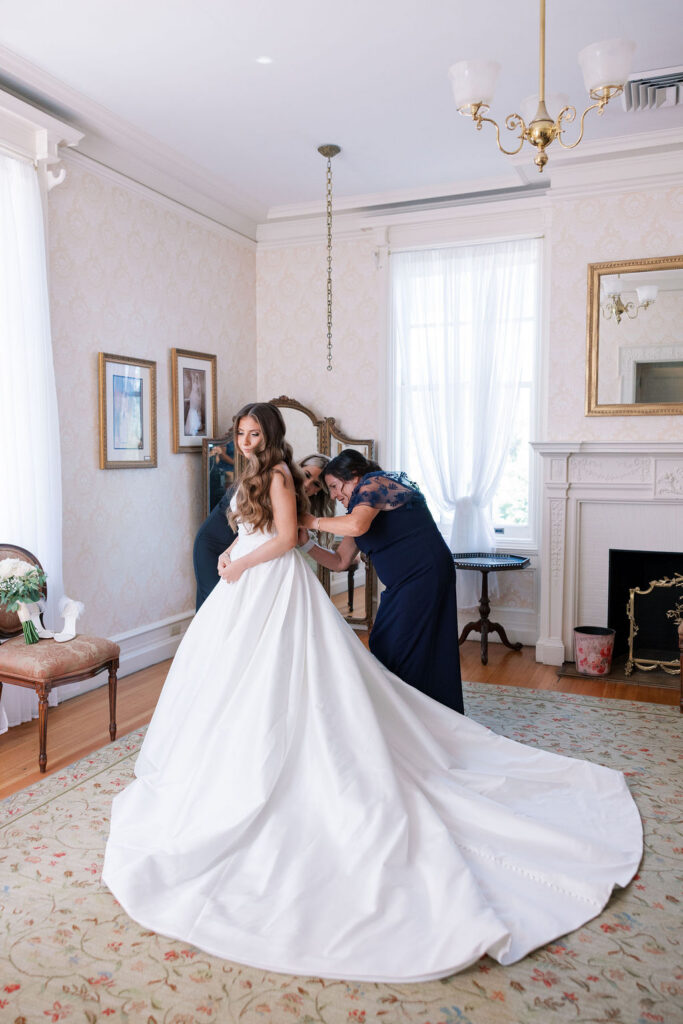 Bride getting into her ballgown wedding dress with help from her mother in the bridal suite at Cairnwood Estate