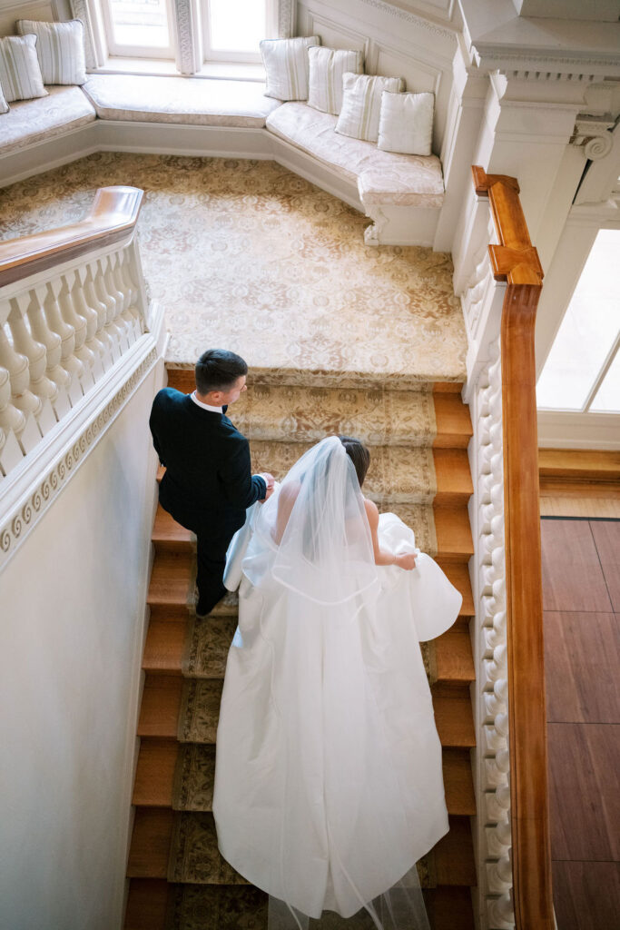 Overhead view of bride and groom descending the carpeted grand staircase at Cairnwood Estate