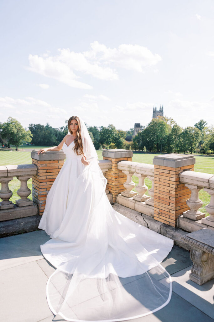 Bride in ballgown on the terrace with Bryn Athyn Cathedral views at a wedding at Cairnwood Estate