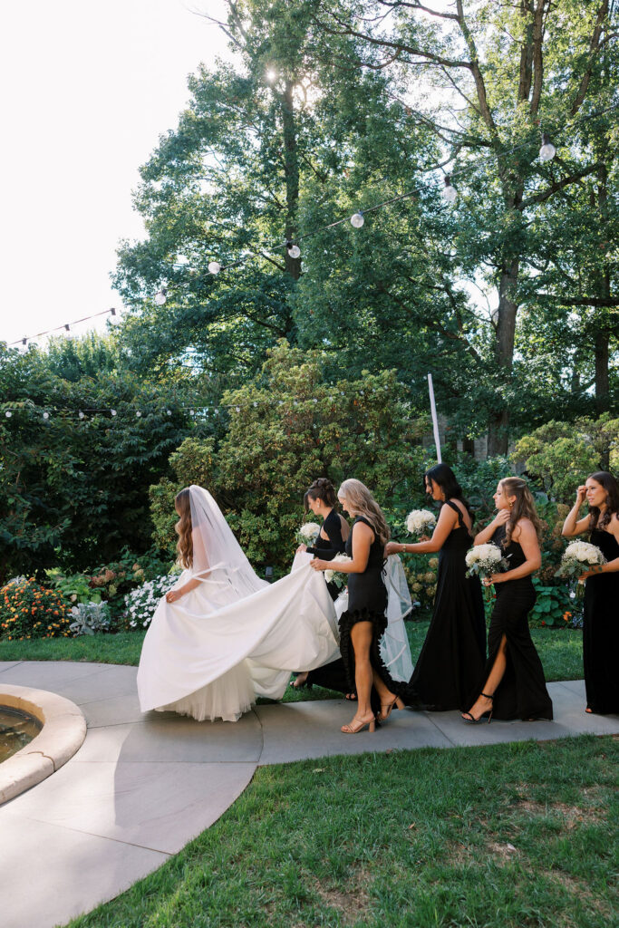 Bridesmaids carrying the bride's train through the fountain garden at a wedding
