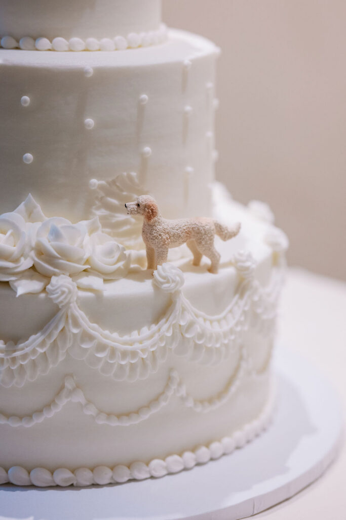 Close-up of the dog figurine cake topper on the white buttercream wedding cake by Bredenbecks bakery