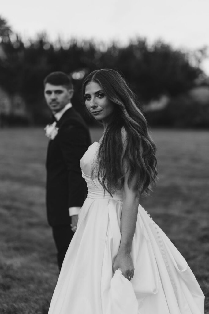 Black and white portrait of the bride looking over her shoulder with the groom at a wedding at Cairnwood Estate