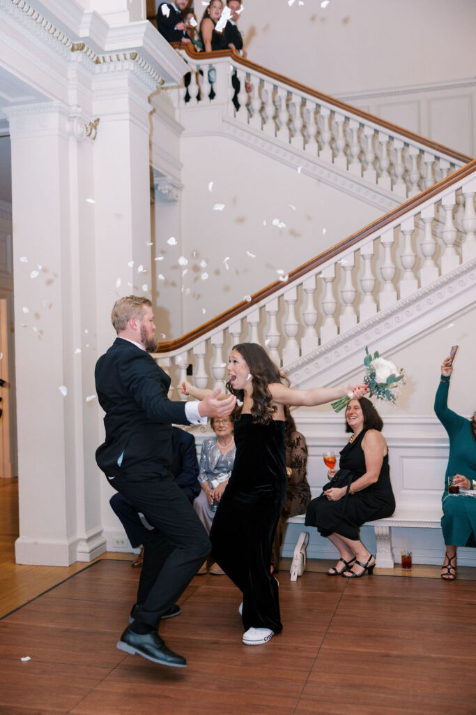 Guests dancing as petals fall on the grand staircase during the reception