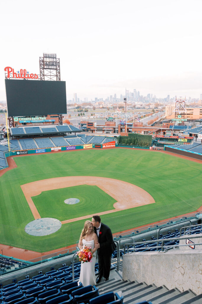 Wide shot of baseball diamond at Citizens Bank Park with bride and groom posing together in the stands
