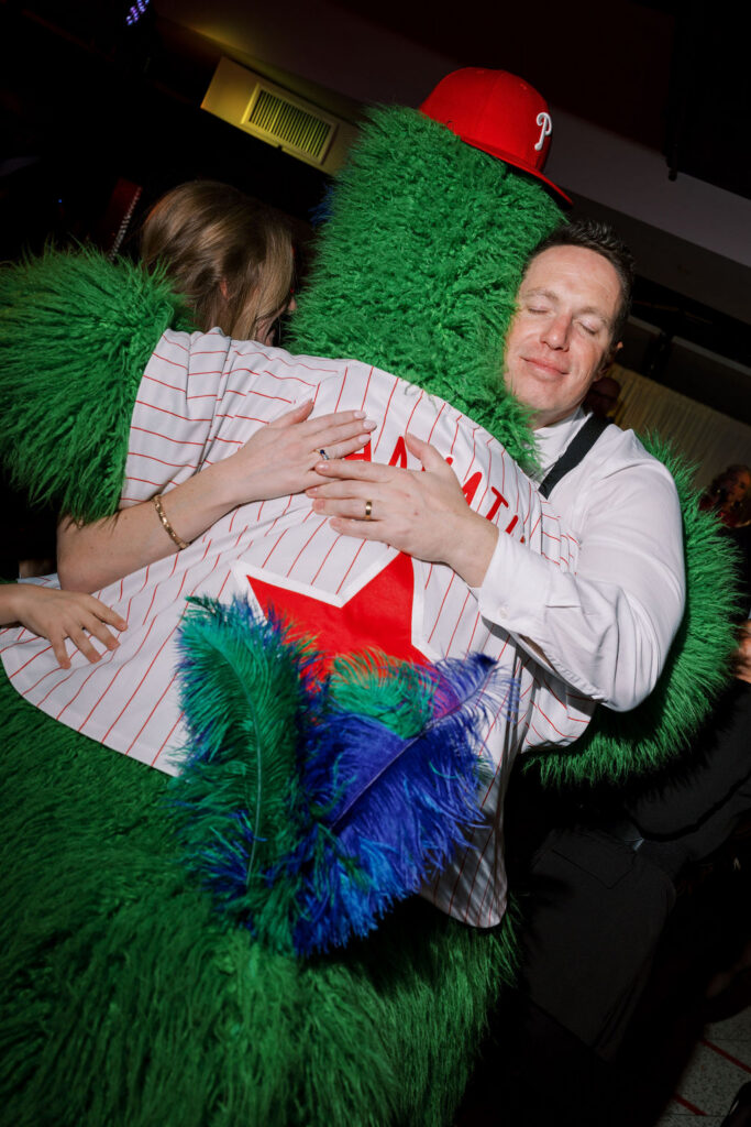 Bride and groom hug Phillies Phanatic mascot at Citizens Bank Park wedding reception