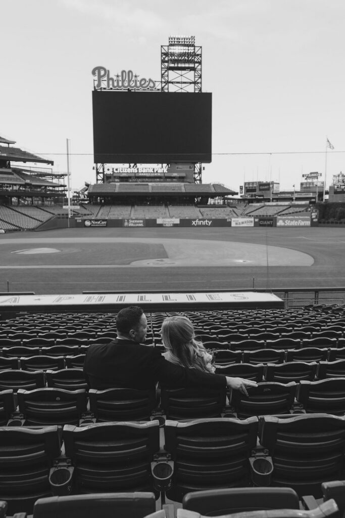Bride and groom sit in the stands at Citizens Bank Park in front of the Phillies sign