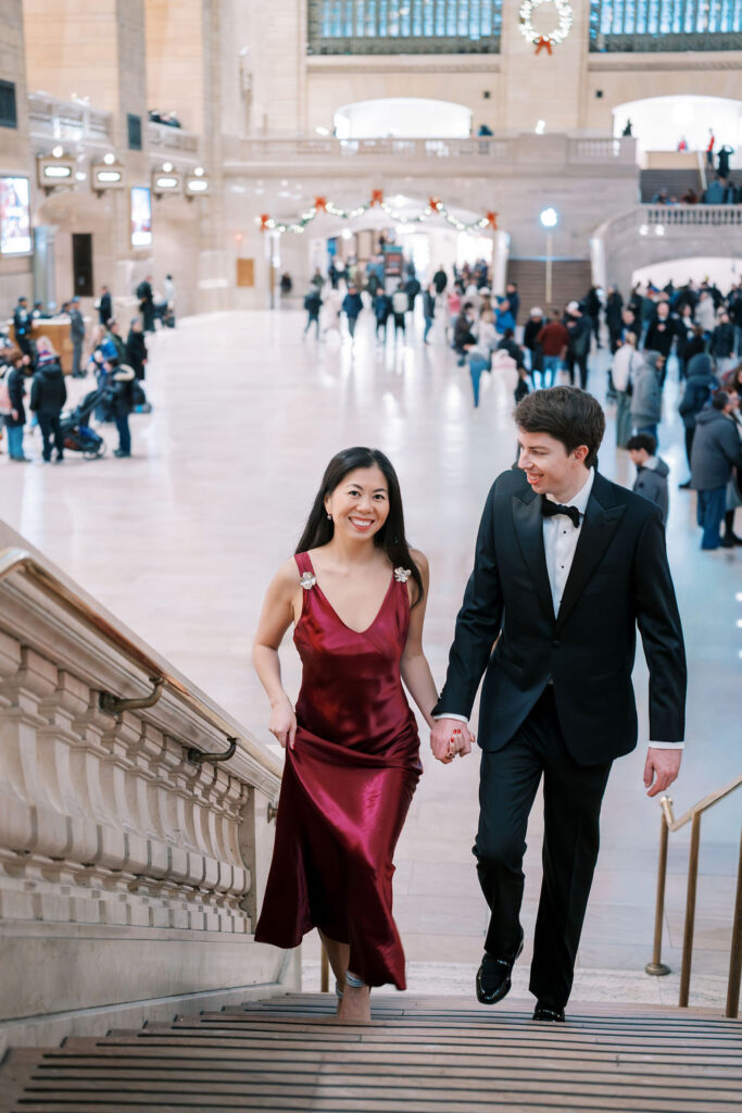 Couple in formalwear walks up a staircase inside Grand Central Station during their NYC engagement photos